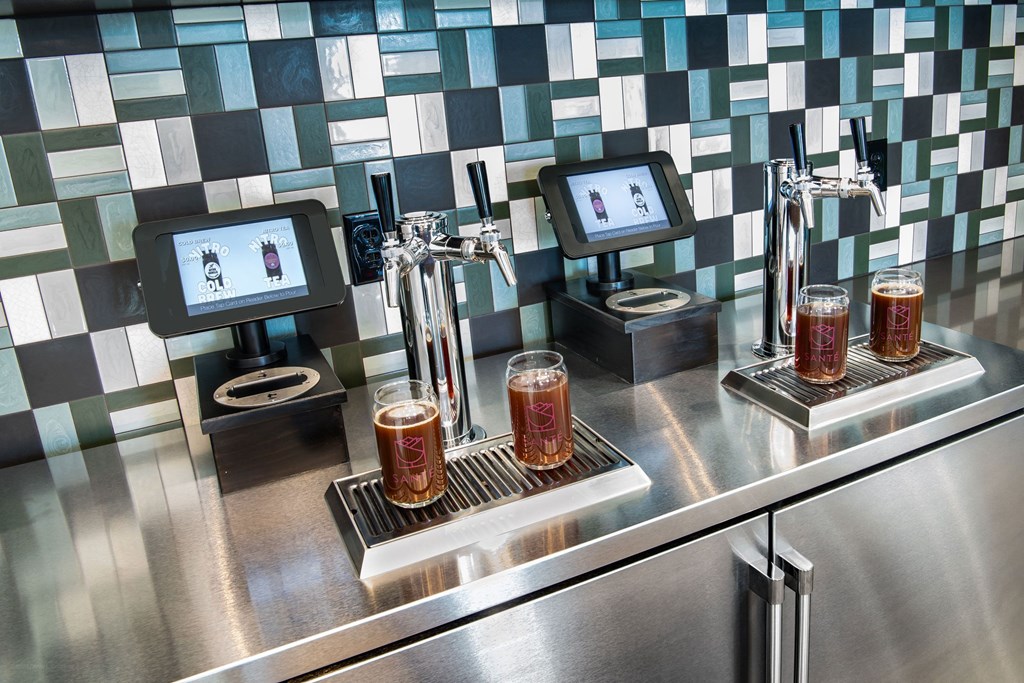 a bar with three glasses of beer on a stainless steel counter