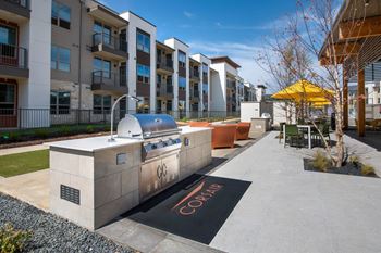 an outdoor entertaining area with a grill in front of an apartment building