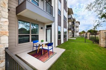 a patio with a table and chairs in front of an apartment building
