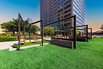 A playground with a swing set and a tall building in the background.