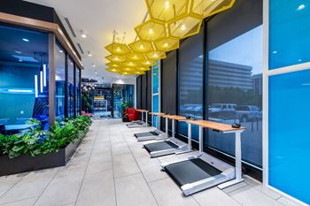 A gym with treadmills and a row of yellow hanging lights.