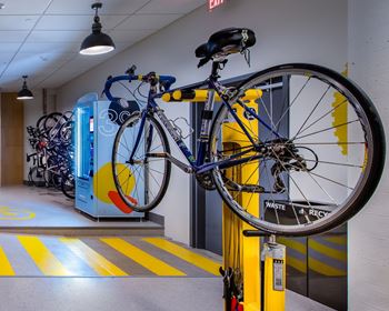 A bicycle is hanging on a yellow rack in a hallway.