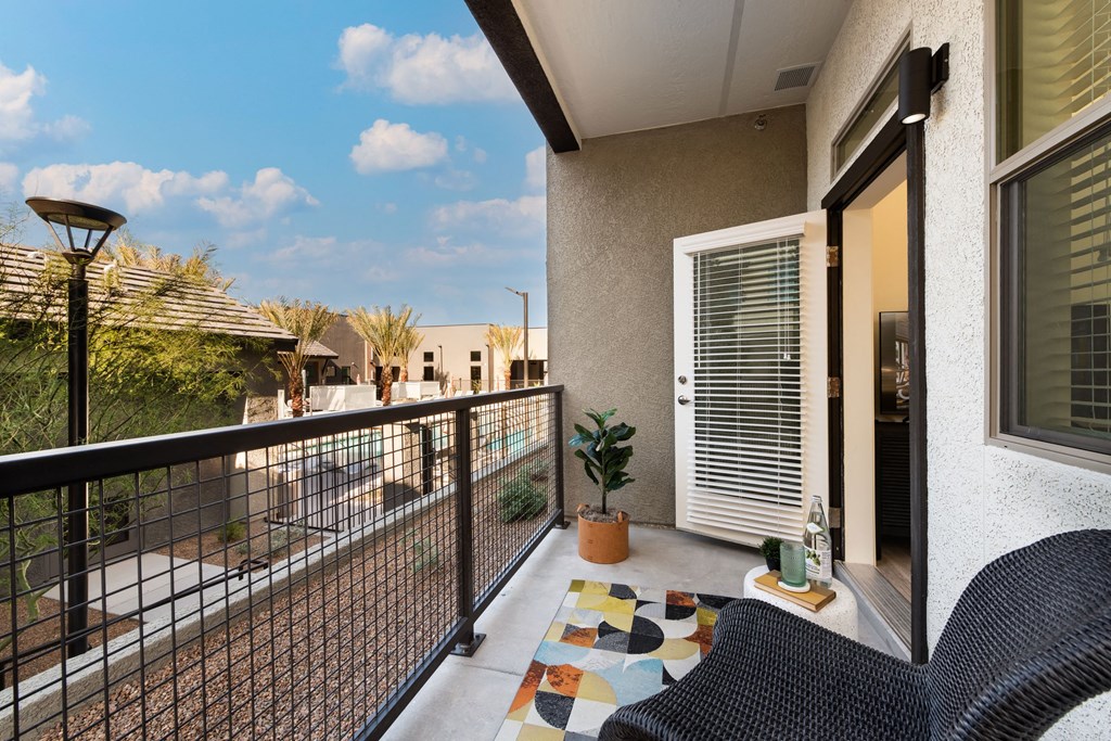 a balcony with a patio and two chairs and a potted plant