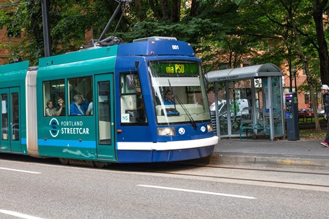 a blue tram is stopped at a bus stop