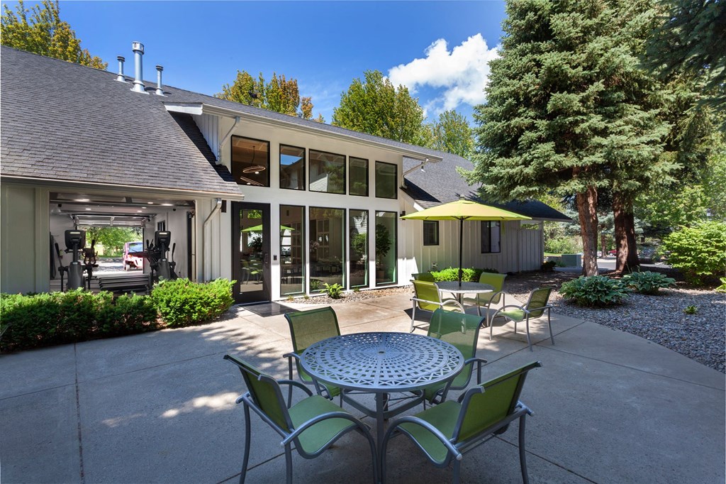 a patio with a table and chairs and a house in the background
