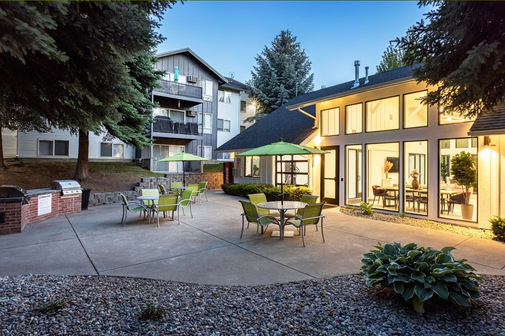 a patio with green chairs and umbrellas in front of a building
