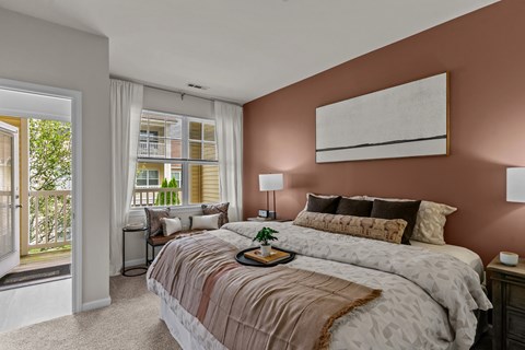 A bedroom with a large bed and a window overlooking a balcony.