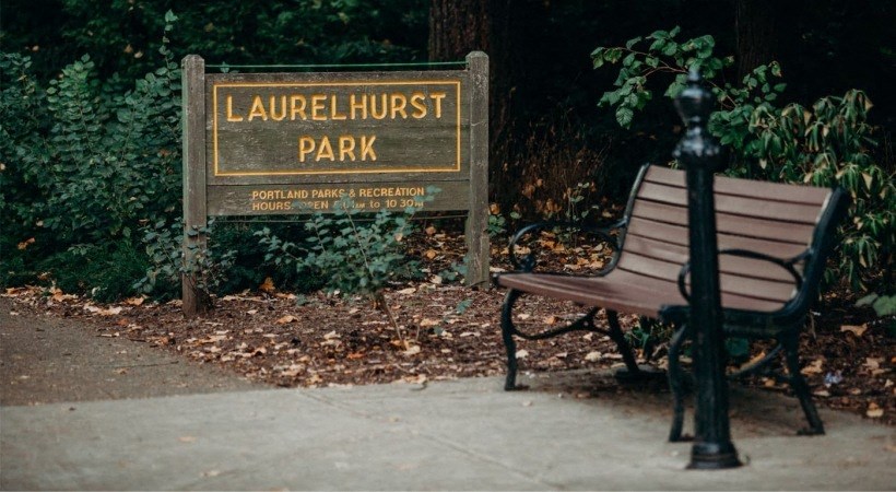 a park bench sitting in front of a park sign