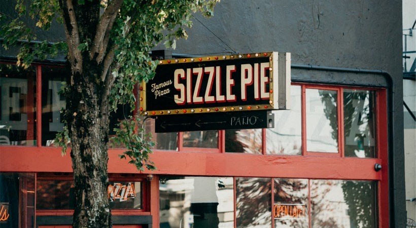 a sign on the side of a building with a tree