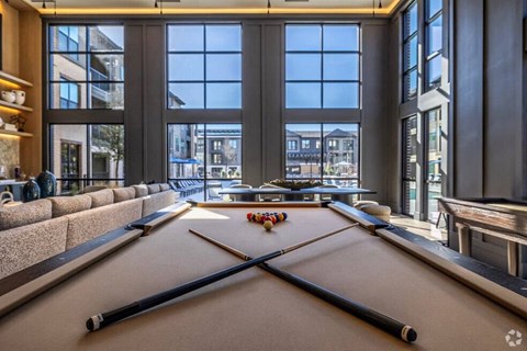 A pool table in a room with large windows.