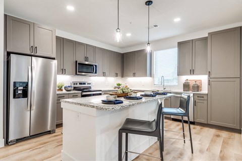 A modern kitchen with a white island and a refrigerator with a digital display.