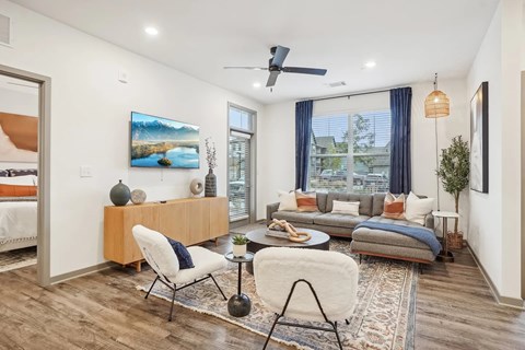 A modern living room with a white sofa, a wooden side table, and a painting on the wall.