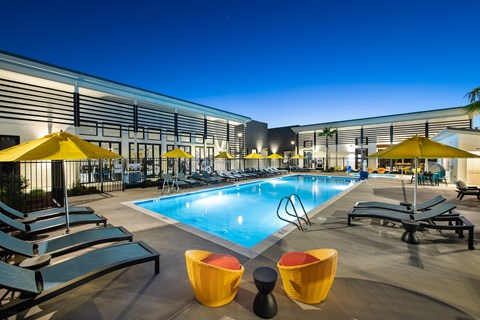 a pool with lounge chairs and umbrellas in front of a building