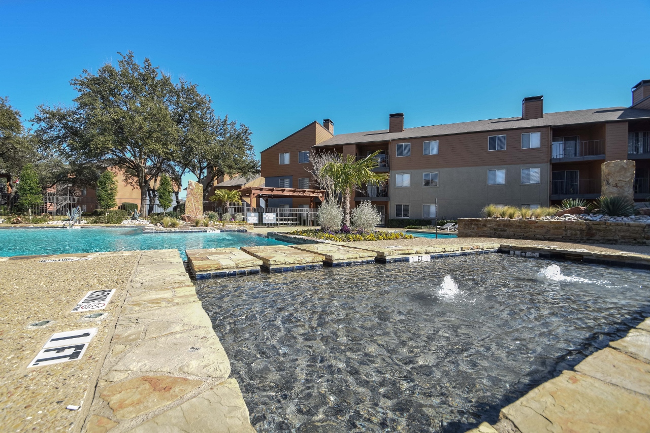 a swimming pool with a fountain in front of an apartment building
