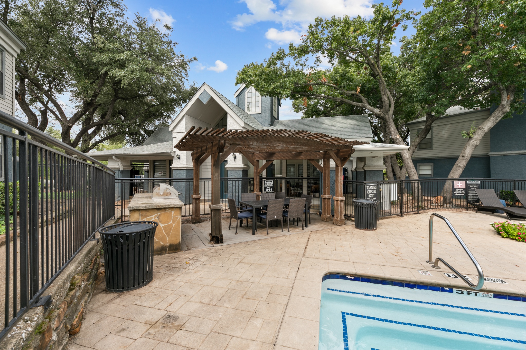 a backyard with a pool and a patio with a table and chairs