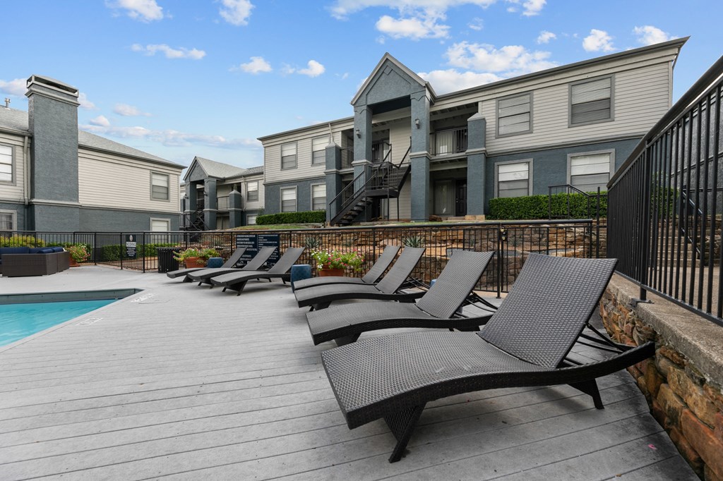 a group of lounge chairs on a deck next to a swimming pool