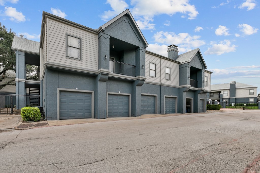 a blue house with garages and a street in front of it