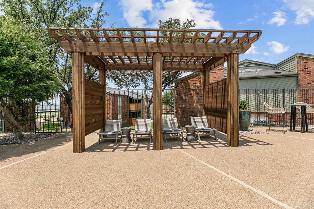 a wooden pergola with lounge chairs on a gravel patio at The Hills at Ironhorse, Texas