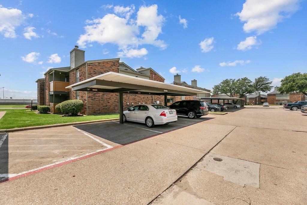 a parking lot with cars parked in front of a brick building at The Hills at Ironhorse, North Richland Hills