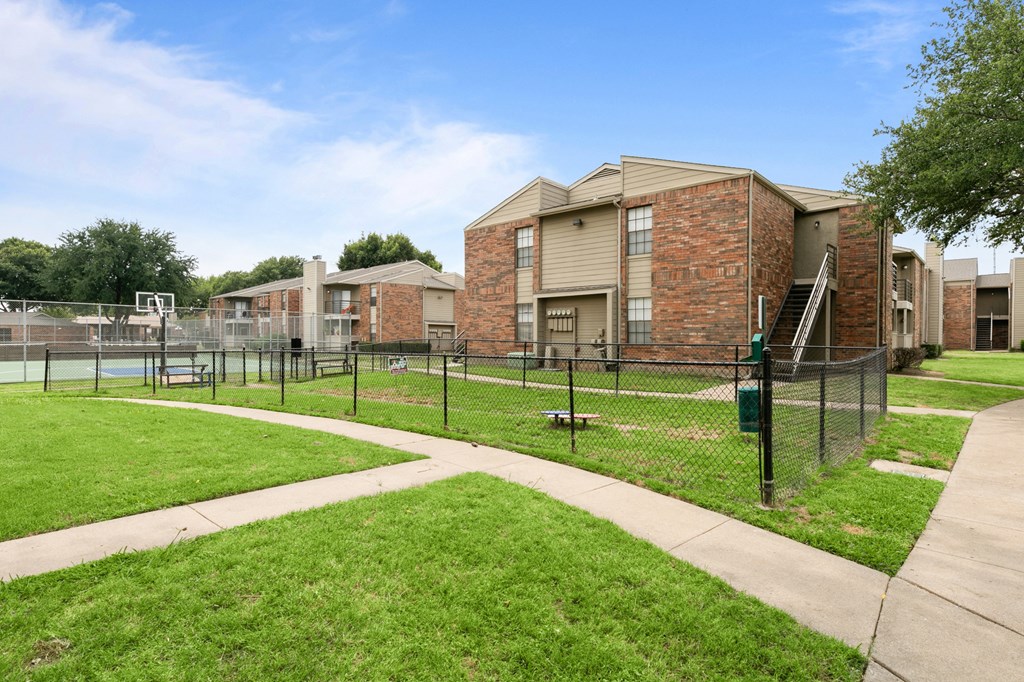 a fenced in area with a tennis court in front of a building at The Hudson, Texas, 76180