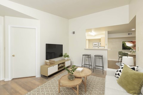 A living room with a white couch, a wooden coffee table, and a television on a cabinet.
