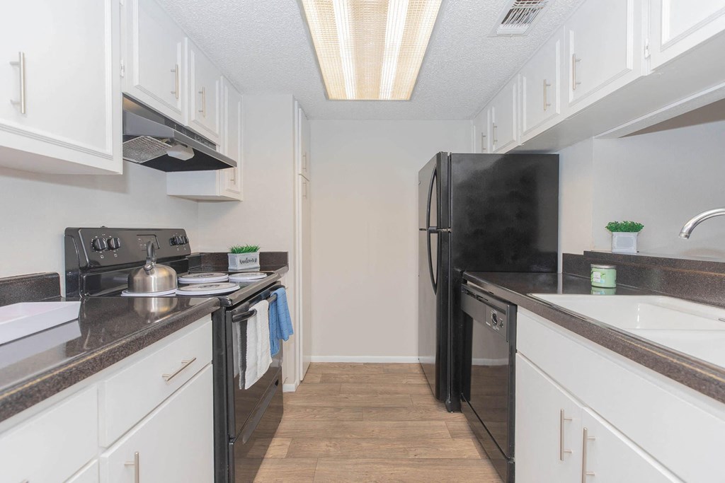 a kitchen with white cabinets and a black refrigerator
