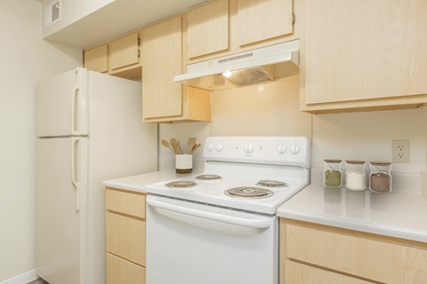 A white stove and refrigerator in a kitchen with wooden cabinets.
