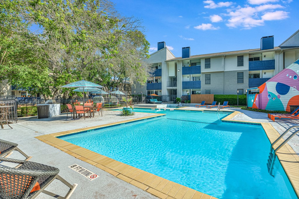 a swimming pool with an apartment building in the background at Peaks at Northwest Hills Apartments, Austin