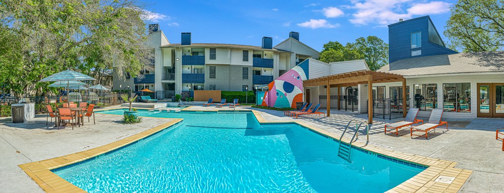 our apartments have a large swimming pool with chairs and umbrellas at Peaks at Northwest Hills Apartments, Austin, TX 78731