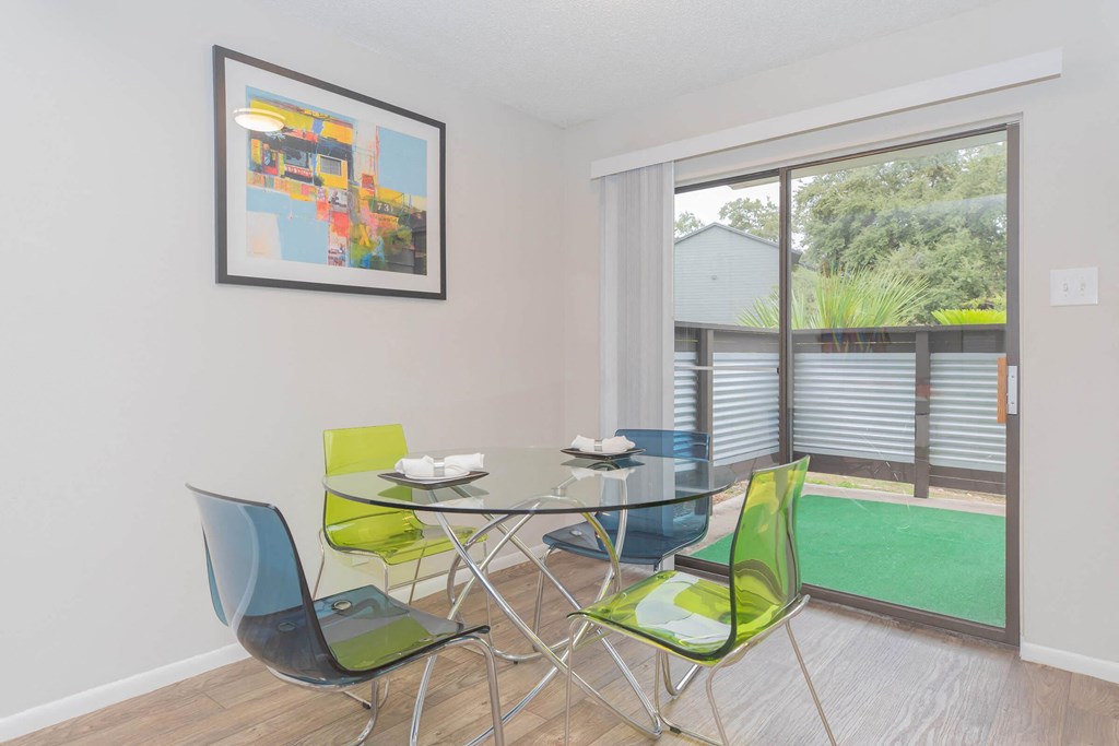 a dining room with a glass table and chairs and a large window