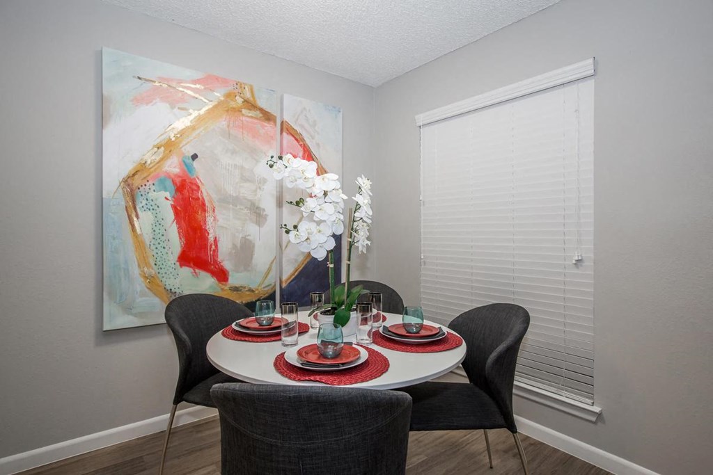 a dining room with a table and chairs and a painting on the wall