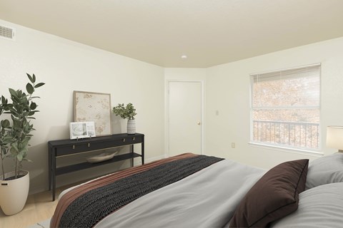 A bedroom with a bed, a plant, and a picture frame on a table.
