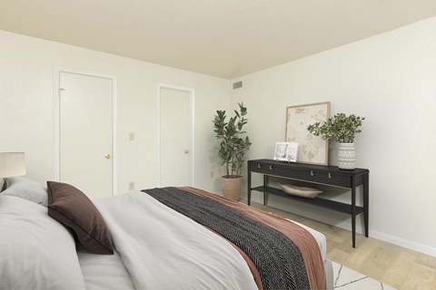 A bedroom with a bed, nightstand, and a plant.