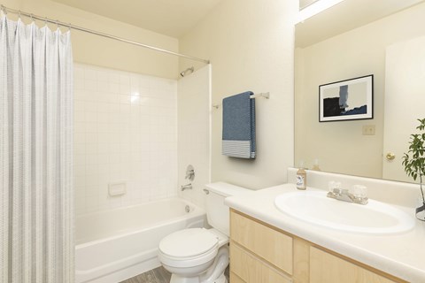 A white toilet sits next to a white bathtub in a bathroom.