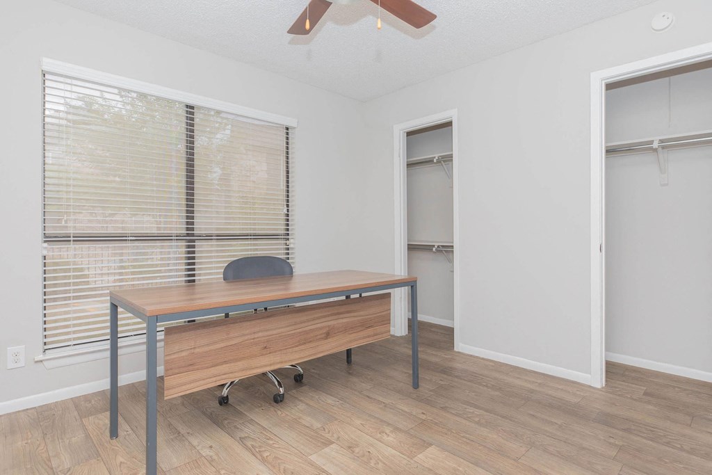 a room with a desk and a large window and a door to a closet