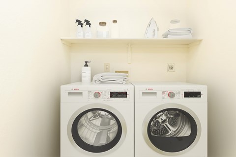 Two white front loading washing machines in a laundry room.