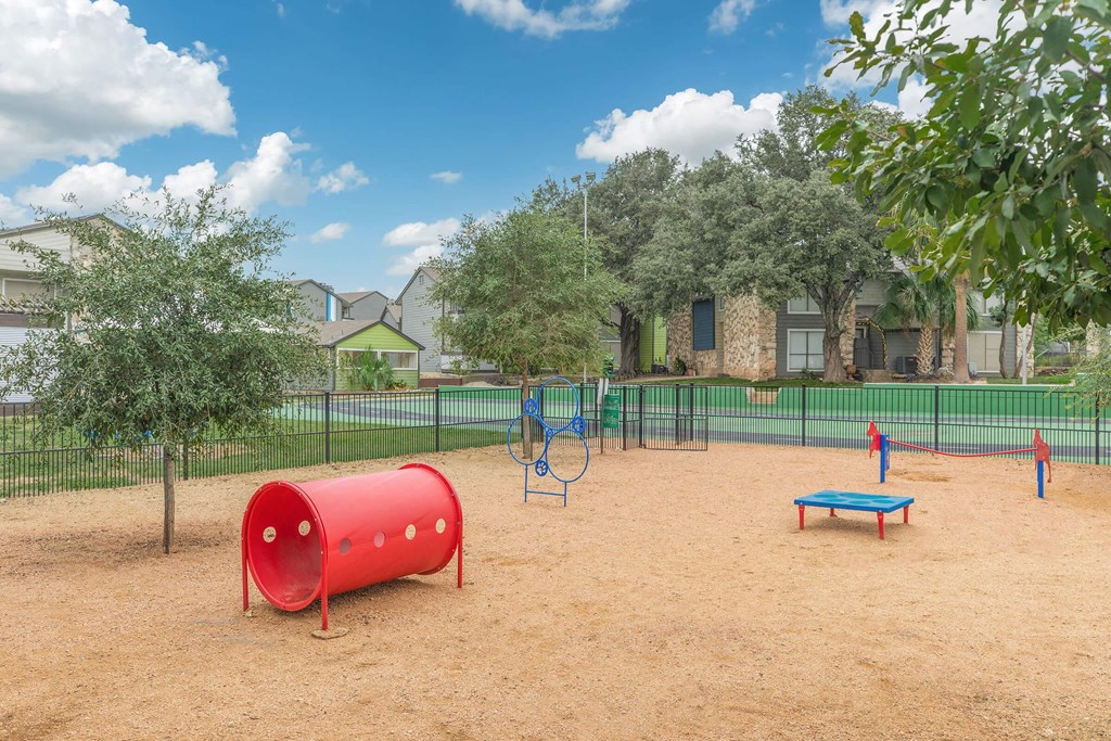 a playground with a seesaw and a bench in front of houses