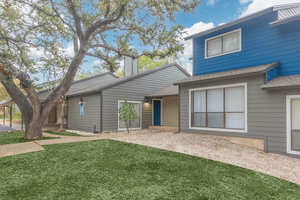 a blue and gray house with a yard and a tree