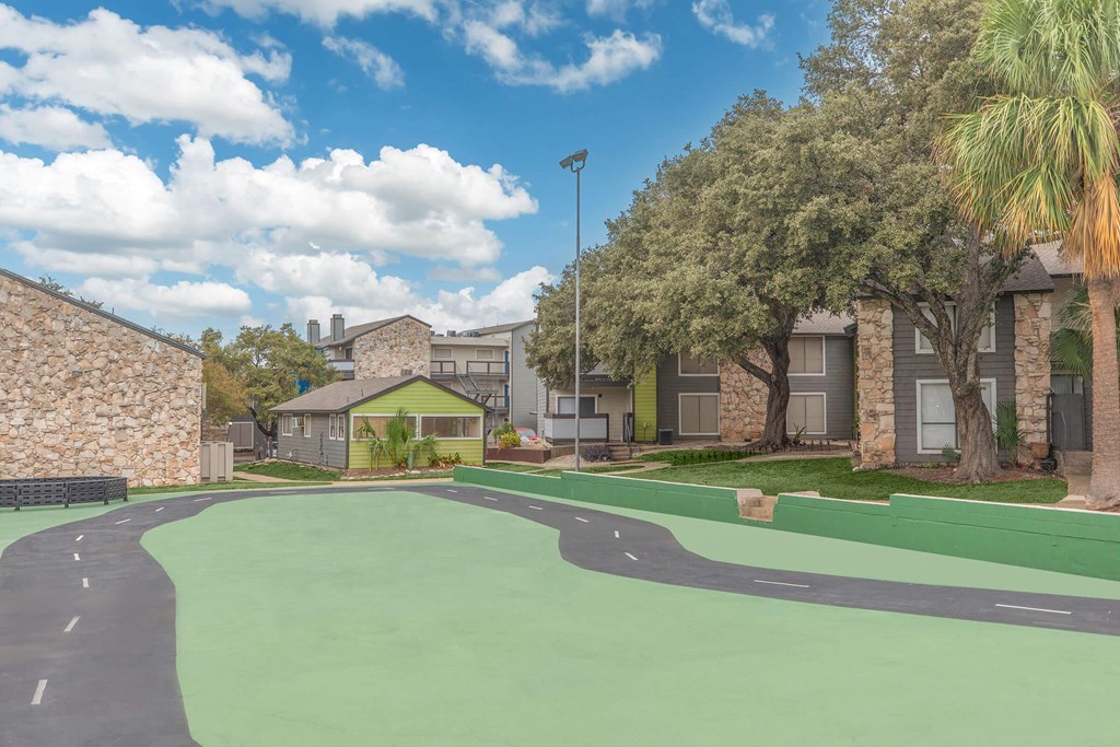 a green court in front of a building with apartments in the background