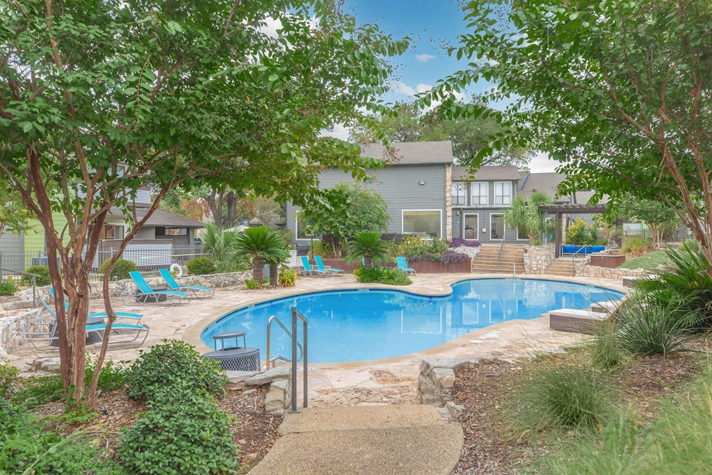 a swimming pool with trees and chairs around it