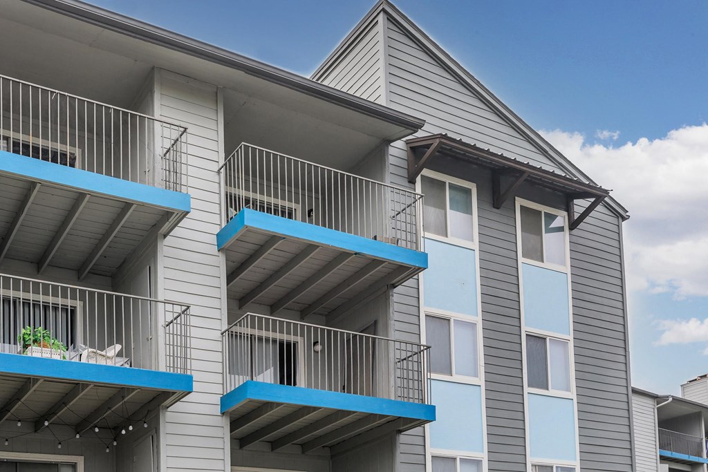 a gray apartment building with blue balconies