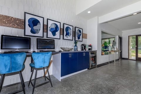a living room with blue chairs and a counter with televisions