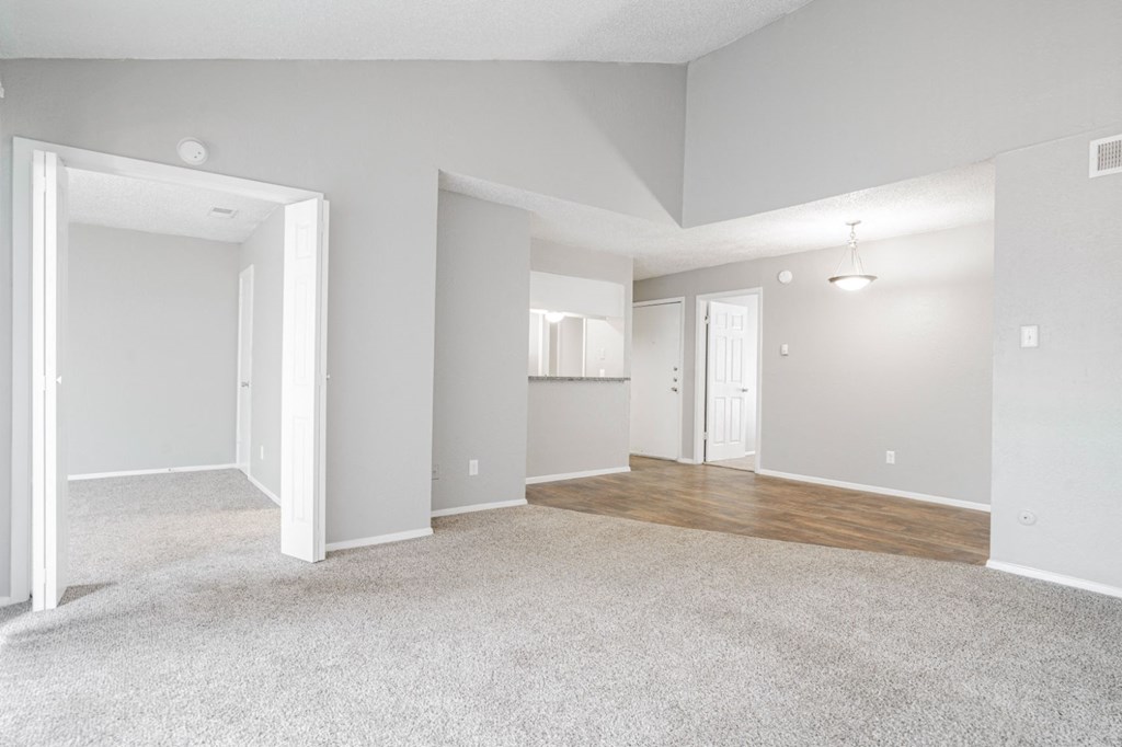 the spacious living room and dining room of an apartment with white walls