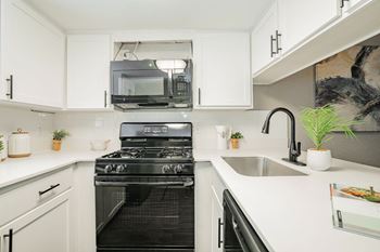 a white kitchen with a stove and a microwave at Aero White Rock, Texas, 75238