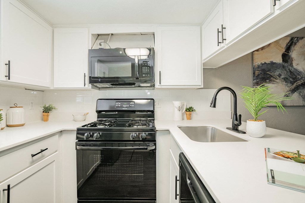 a white kitchen with a stove and a microwave at Aero White Rock, Dallas, Texas