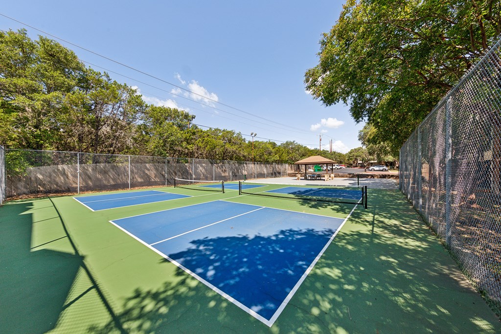 a pickleball court with blue and green courts and a fence