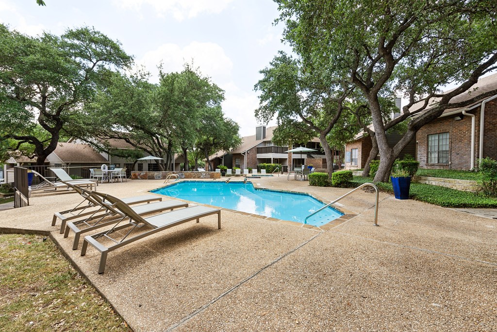 Pool with lounge chairs and trees at Carmel at Deerfield, Texas