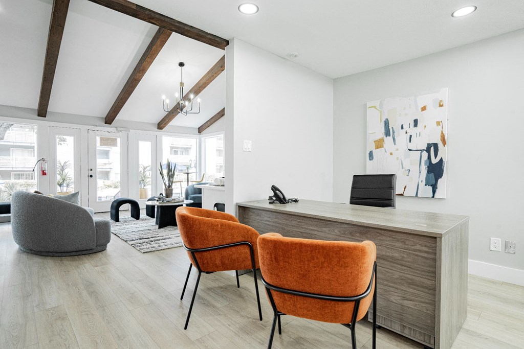 a living room with a desk and chairs