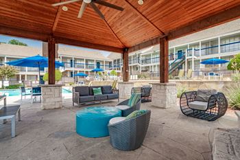 a covered patio with chairs and tables and a pool at Aero White Rock, Dallas