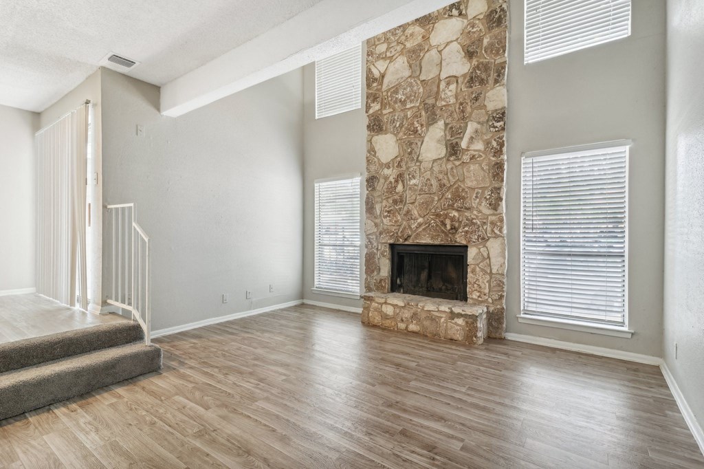 the living room has a large stone fireplace and hardwood floors